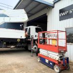 Truck-mounted EWP and scissor lift side by side at workshop showing different machine types